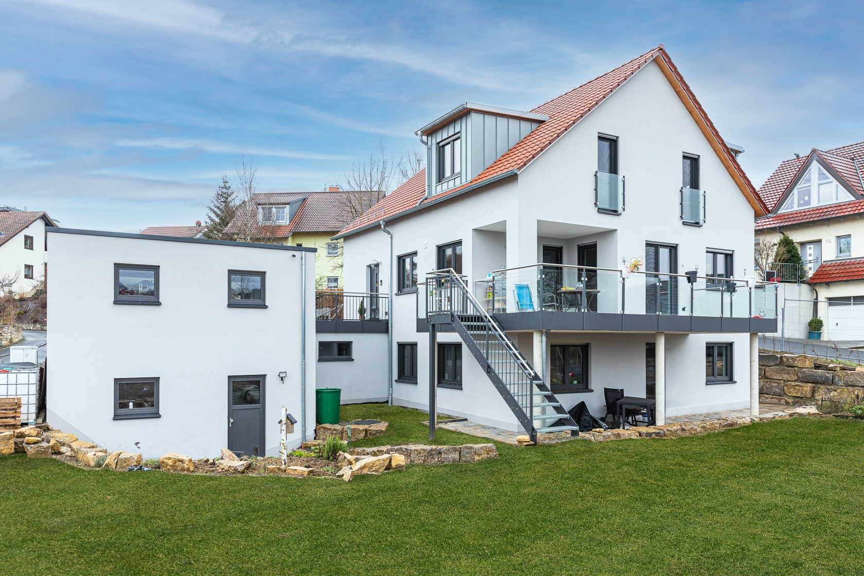 großes weißes Wohnhaus mit Anbau, große Wiese im Vordergrund